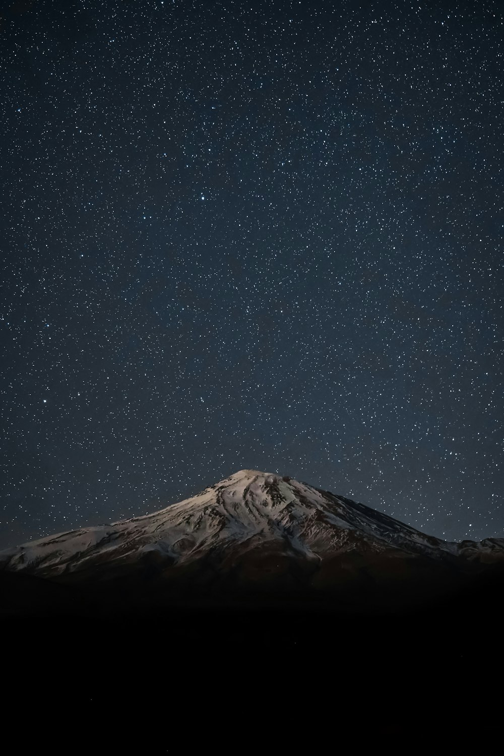 snow covered mountain under starry night