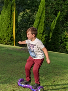 A joyful child riding a hoverboard in a sunny outdoor setting.