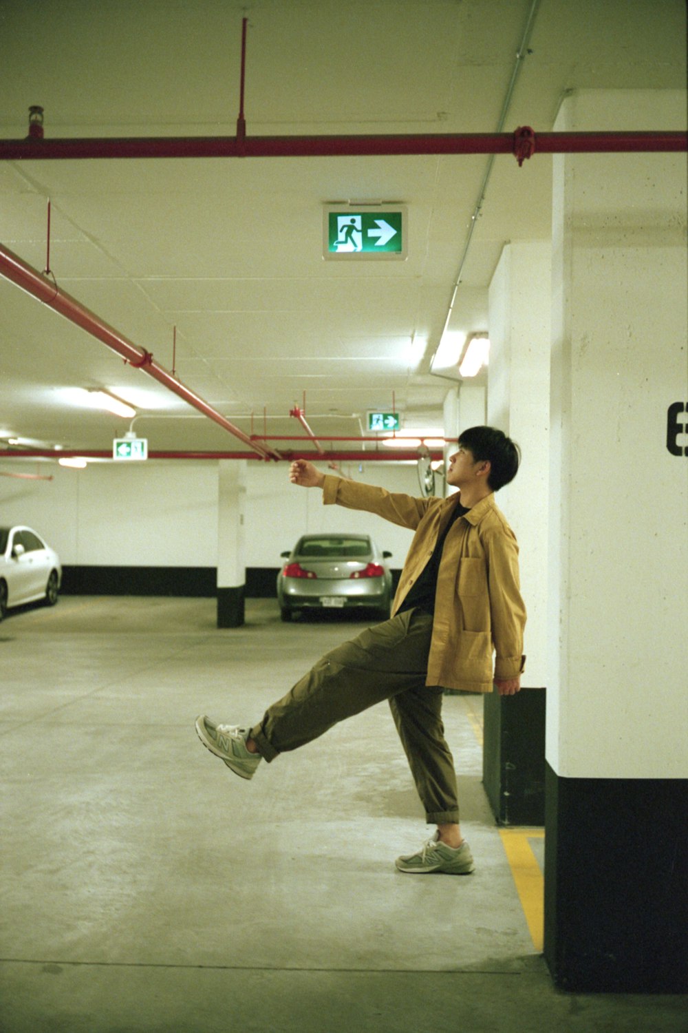 man in brown jacket and gray pants standing on gray floor