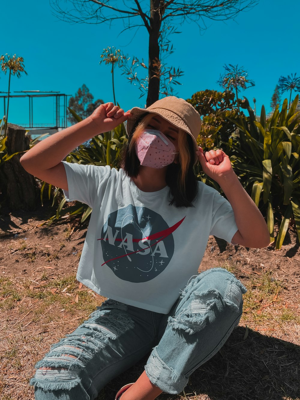 man in white crew neck t-shirt and blue denim jeans sitting on brown sand during