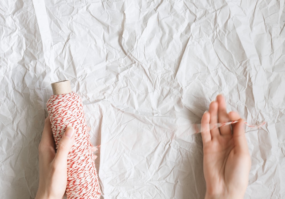 person holding white and pink thread roll