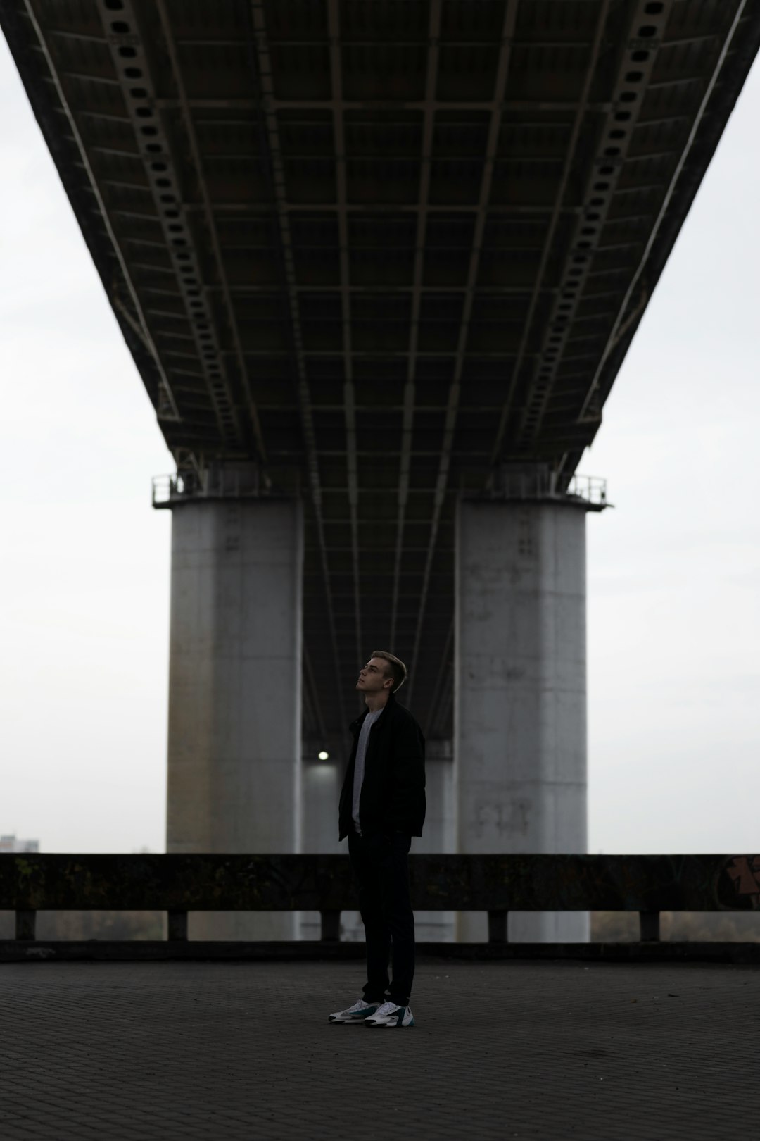 man in black suit standing on bridge during daytime