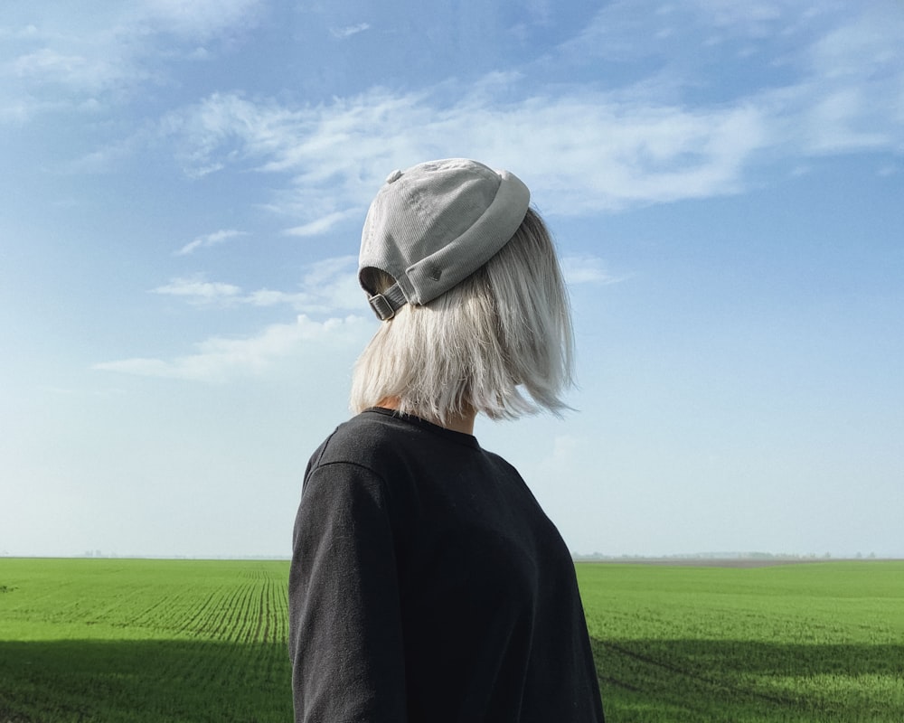 woman in black long sleeve shirt and gray hat standing on green grass field under blue