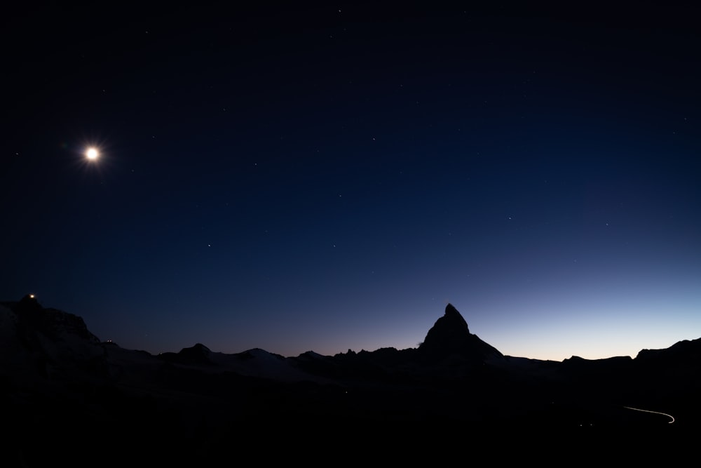 silhouette of mountain under blue sky during night time