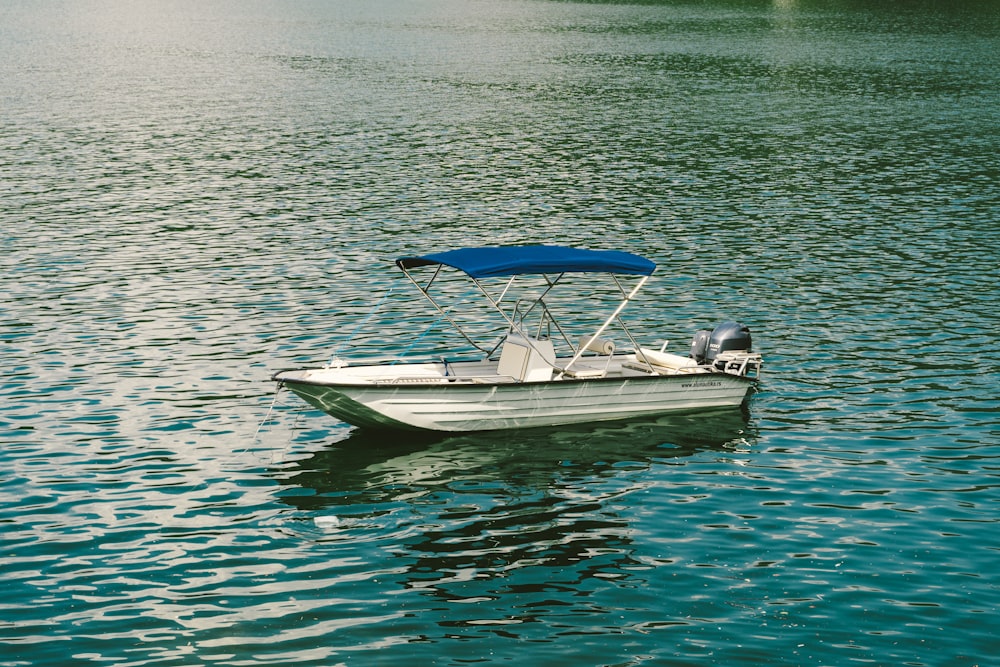 barco branco e azul no corpo de água durante o dia