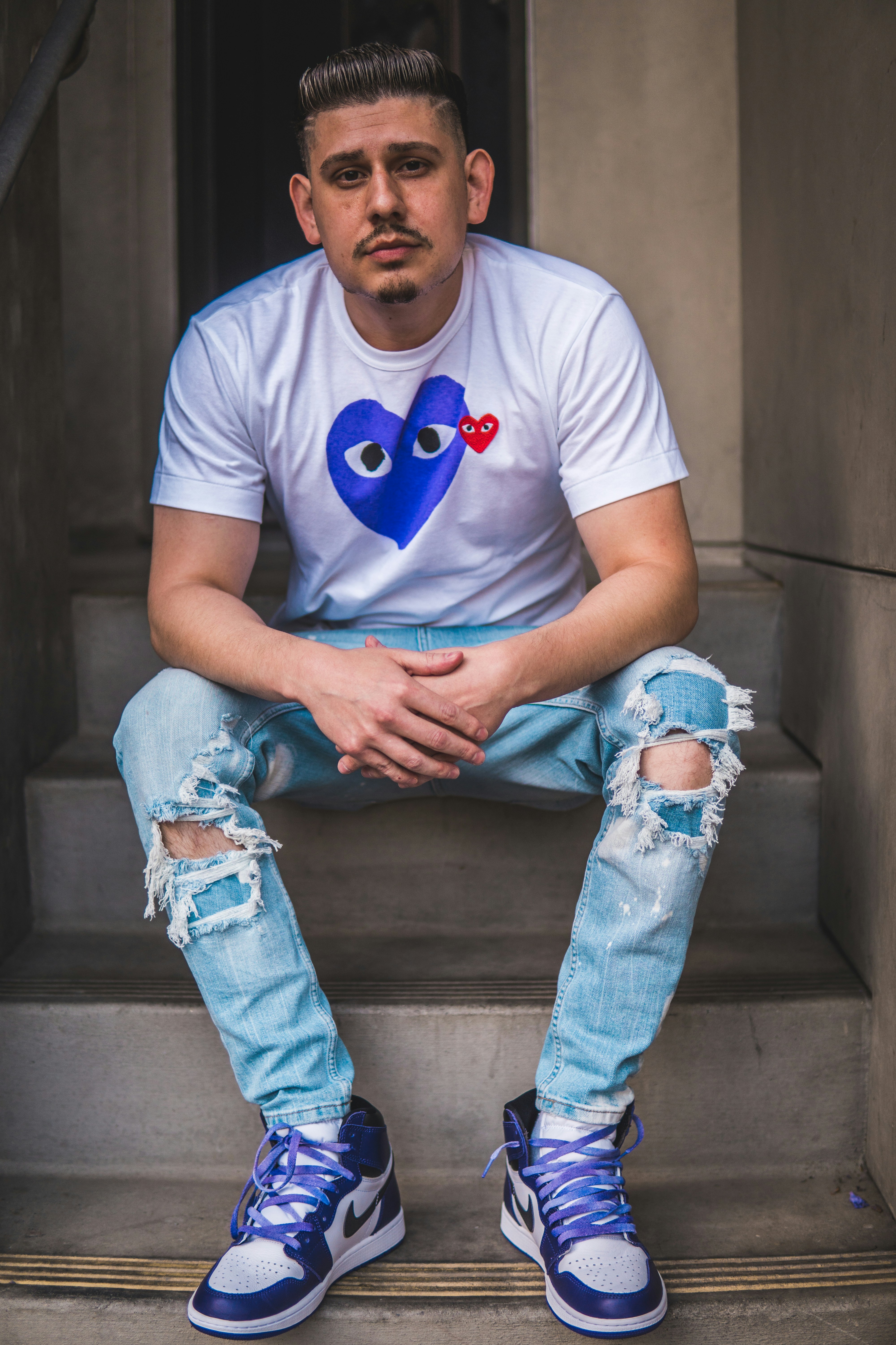 man in blue crew neck t-shirt and blue denim jeans sitting on stairs