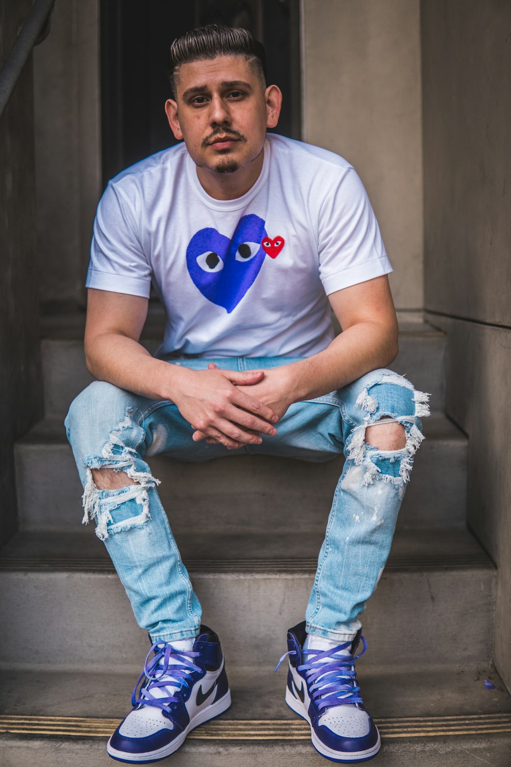 uomo in t-shirt girocollo blu e jeans blu denim seduto sulle scale