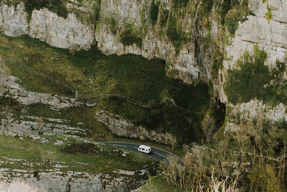 black car on road between rocky mountain during daytime