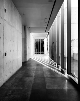 grayscale photo of hallway with glass windows