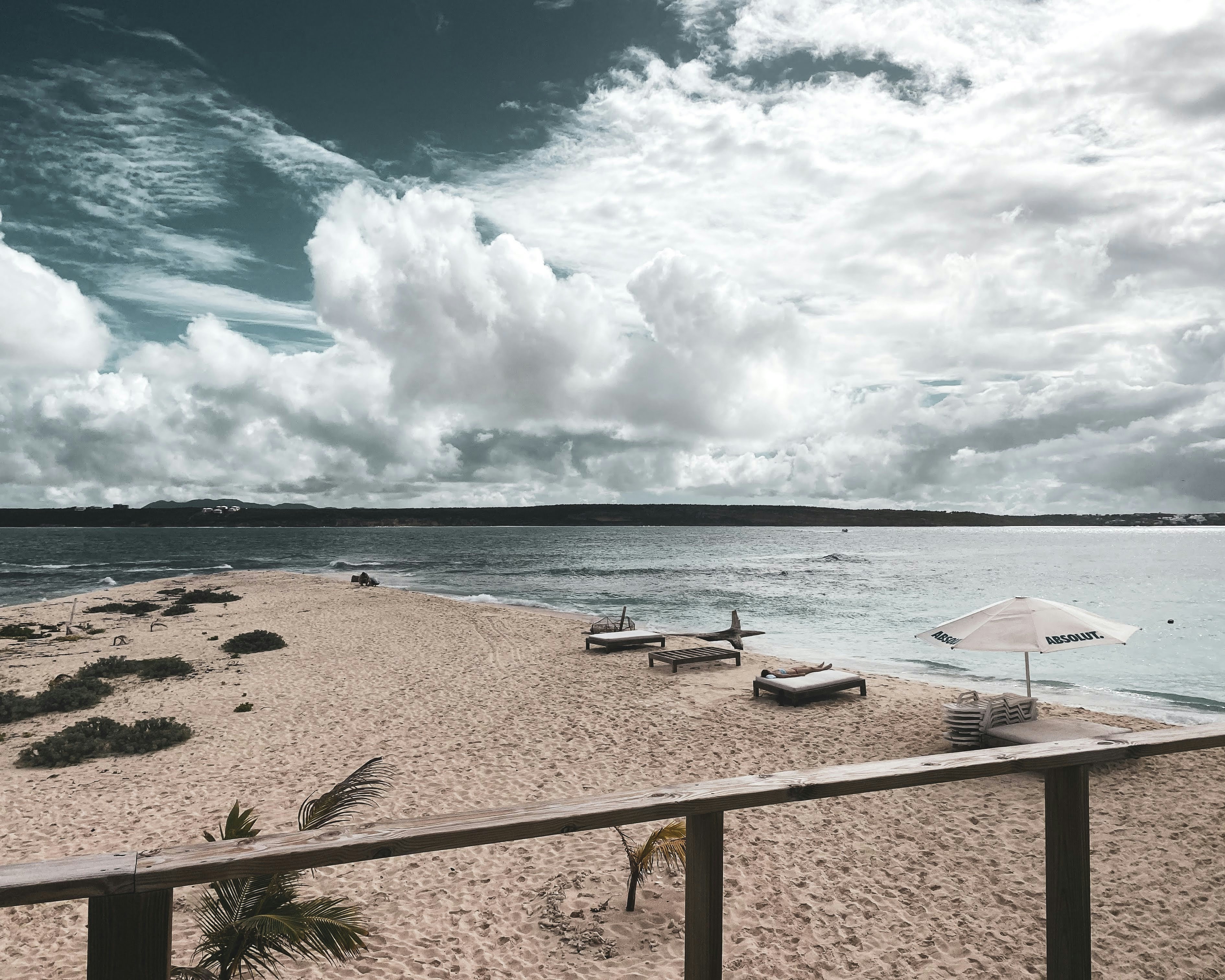 white and black beach lounge chairs on beach shore under blue and white sunny cloudy sky