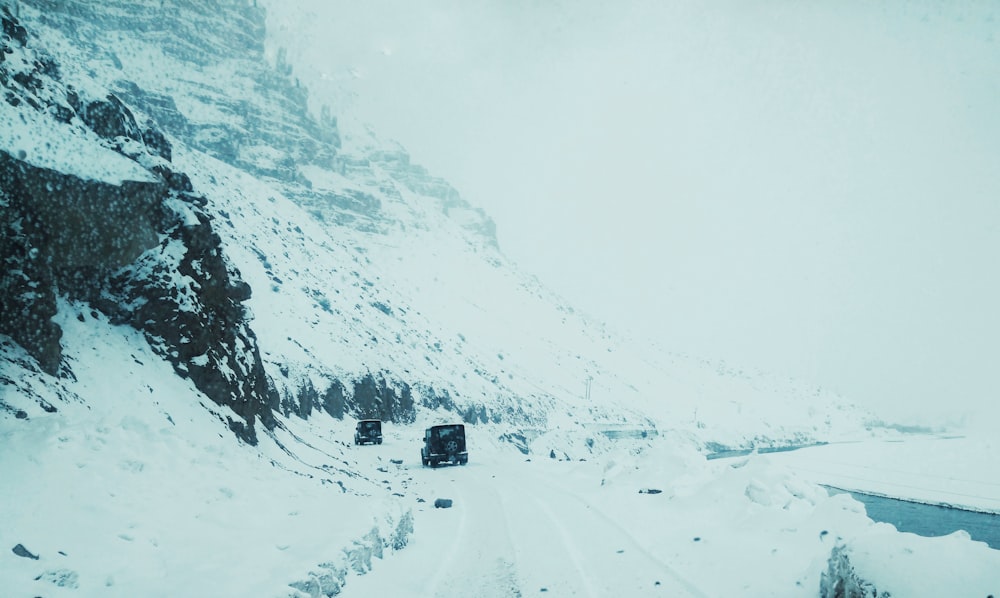 black car on road covered with snow during daytime