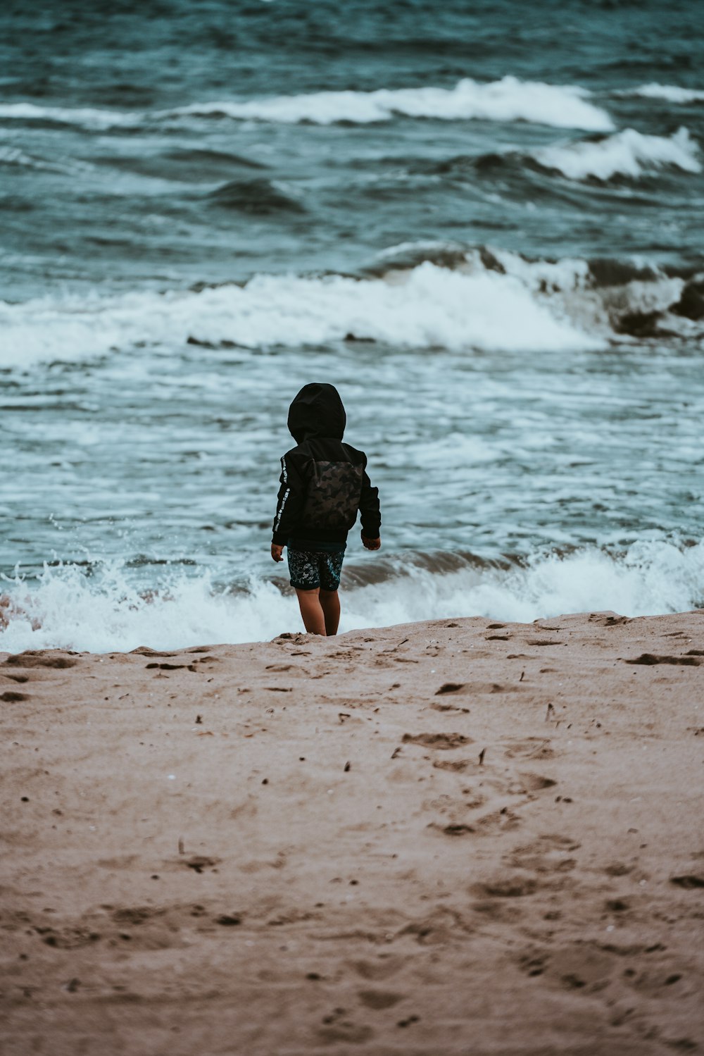 girl in black jacket walking on beach during daytime