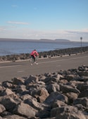 A cyclist riding along a coastal road with ocean views.