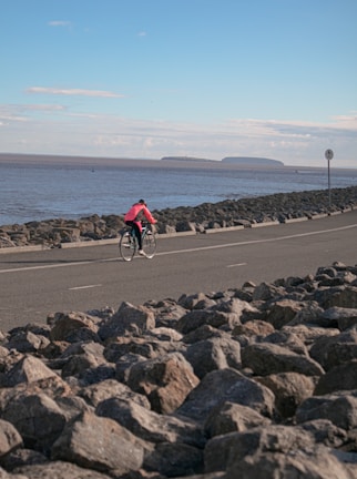 A cyclist riding along a coastal road with ocean views.