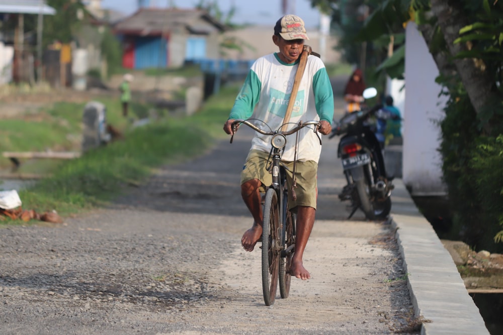 man in white long sleeve shirt riding bicycle on road during daytime