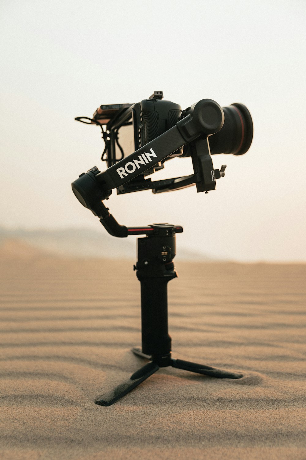 macchina fotografica nera su treppiede su sabbia marrone durante il giorno