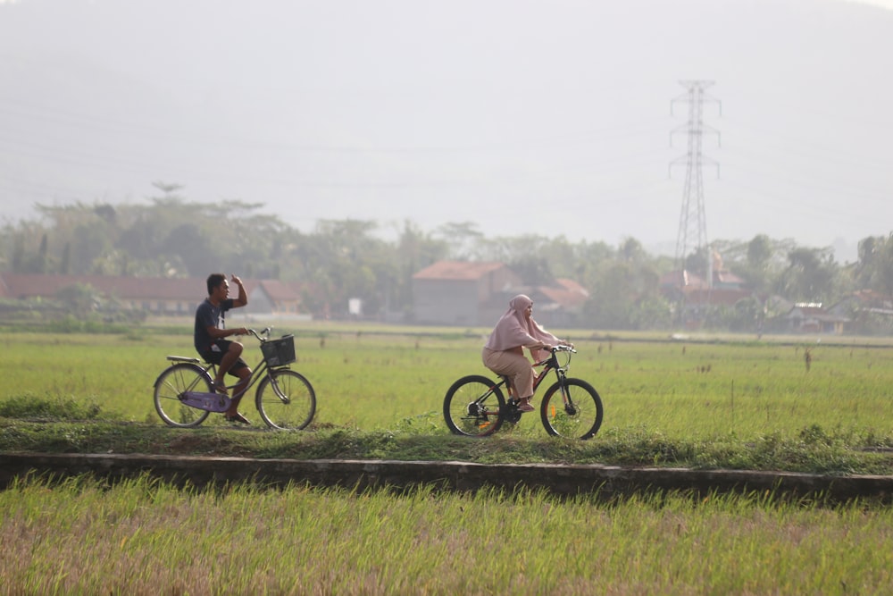 man and woman riding bicycle on green grass field during daytime