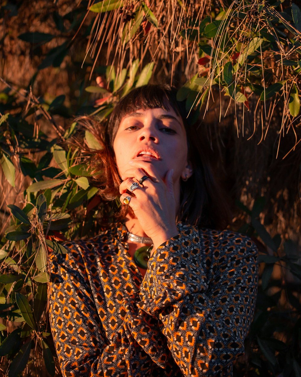 woman in black and brown leopard print long sleeve shirt standing near green plants