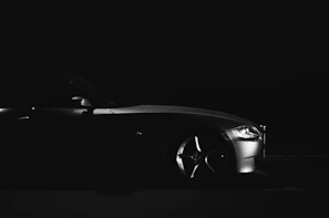 A side profile of a modern project car in mid-restoration, illuminated by soft, directional light emphasizing its curves