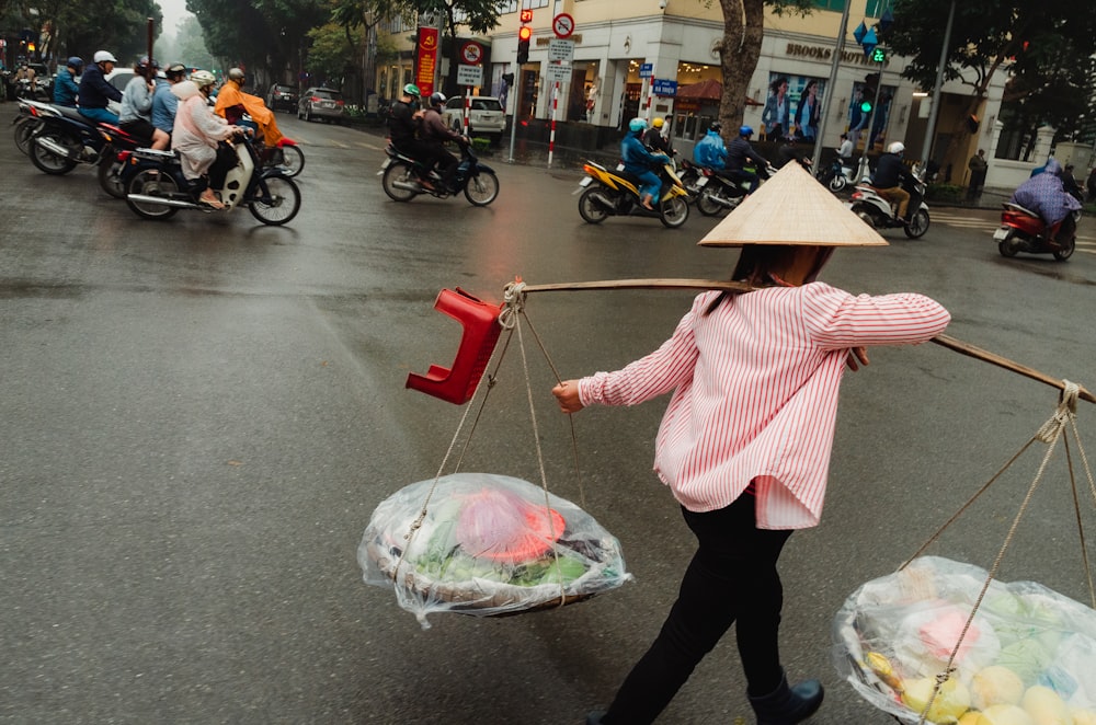 woman in pink and white stripe long sleeve shirt and black pants holding umbrella