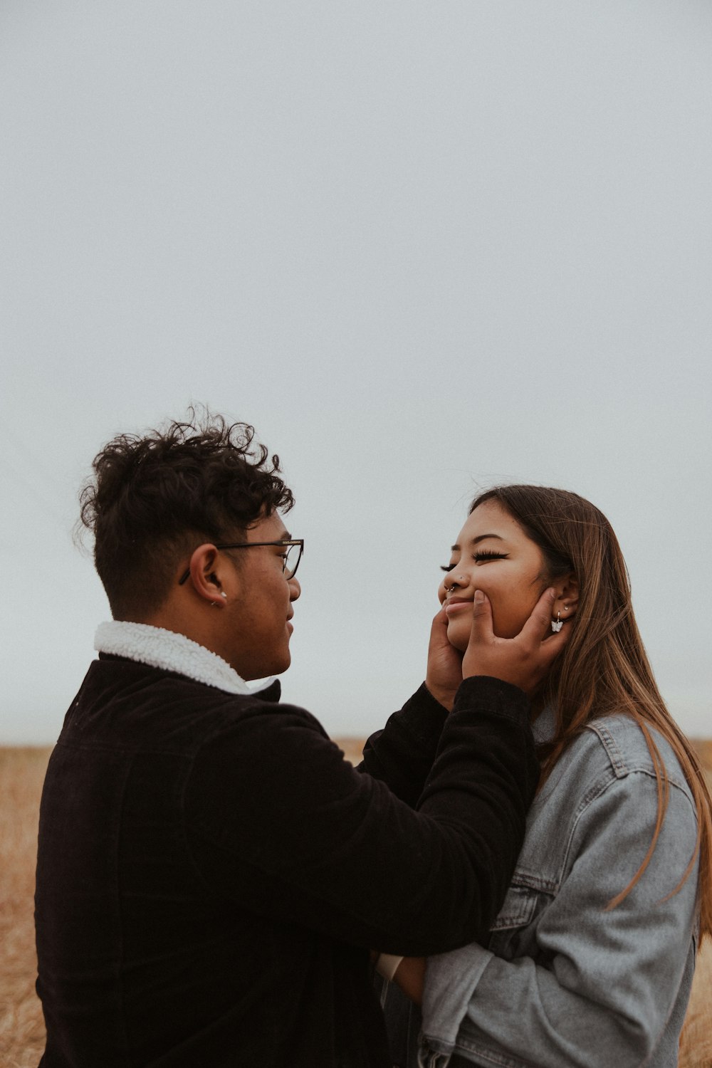 man in black sweater kissing woman in white shirt