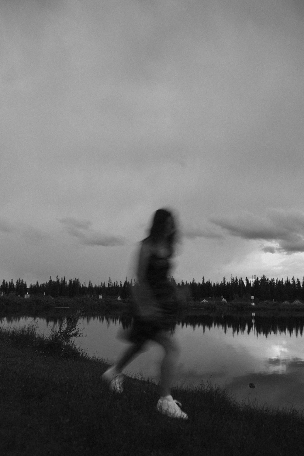 woman in black tank top and black pants standing on grass field near lake