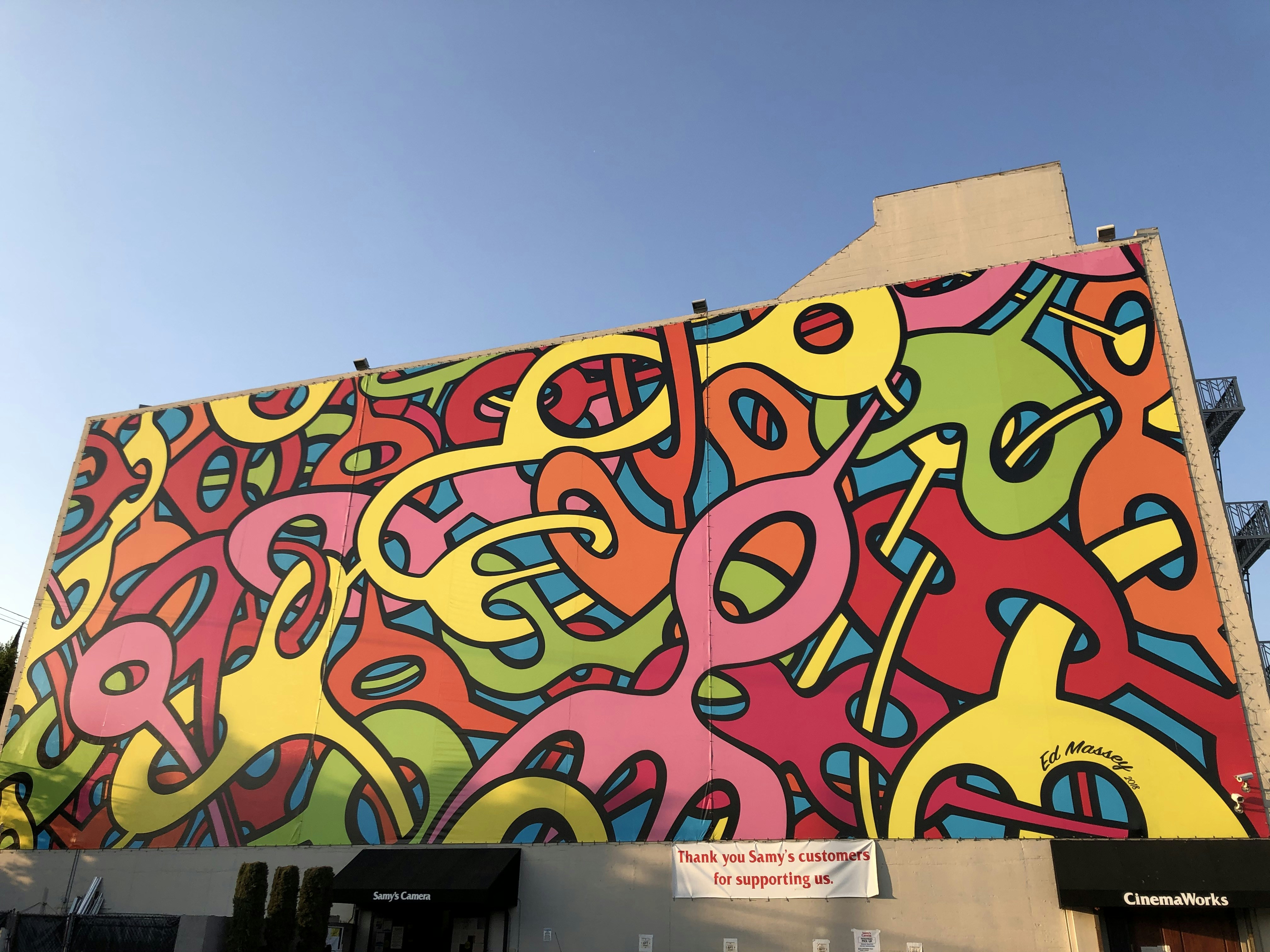 Colorful mural painting on building wall, bright urban daylight, vivid saturated colors
