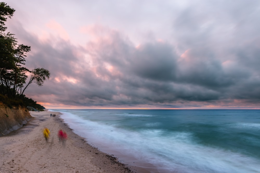 people on beach under cloudy sky during daytime