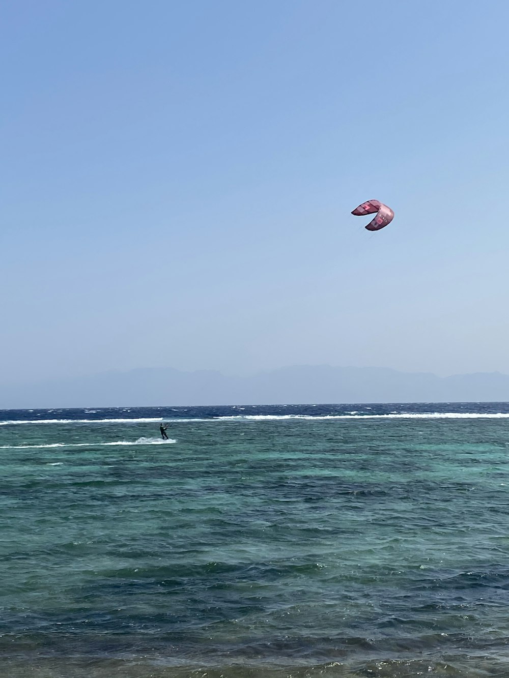 red and white kite surfing on sea during daytime