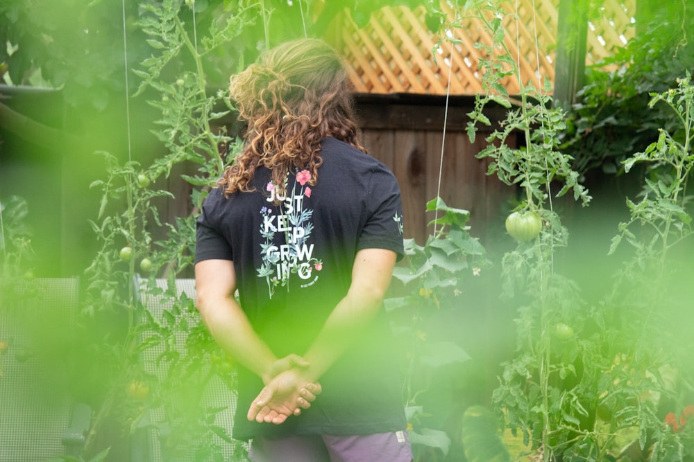 woman in black t-shirt standing beside green plant