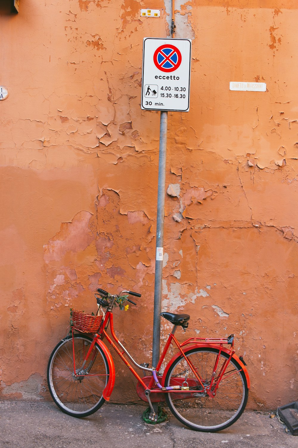 red city bike beside brown wall