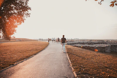 Visitors walking along a cobblestone path beside the monument during a golden sunset.