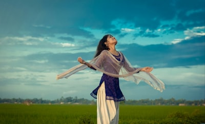 woman in white and blue dress standing on green grass field during daytime mali teams background