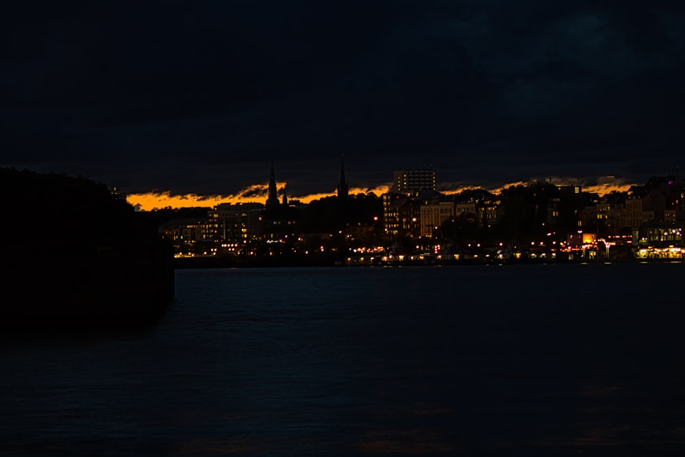 city skyline across body of water during night time