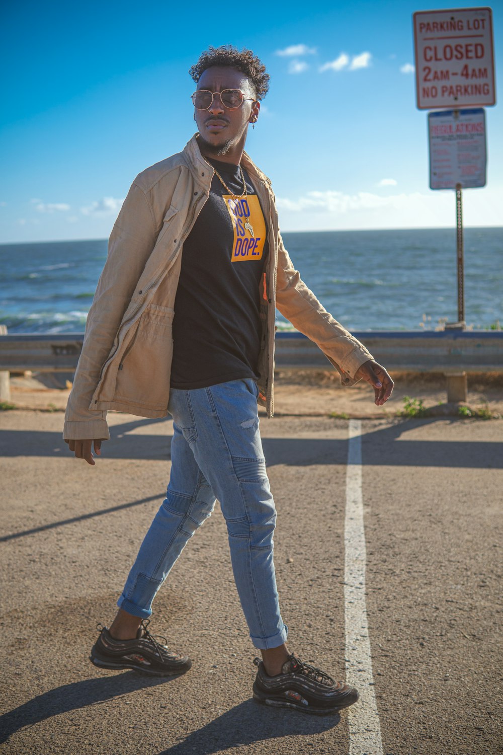 man in brown jacket and blue denim jeans standing on gray concrete road during daytime