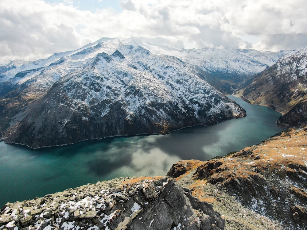 green and white mountain beside body of water during daytime