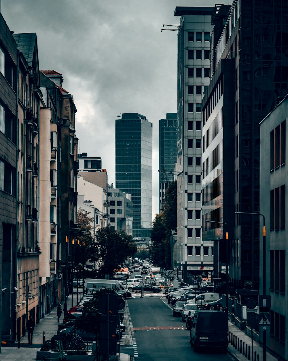 cars parked on side of the road near high rise buildings during daytime