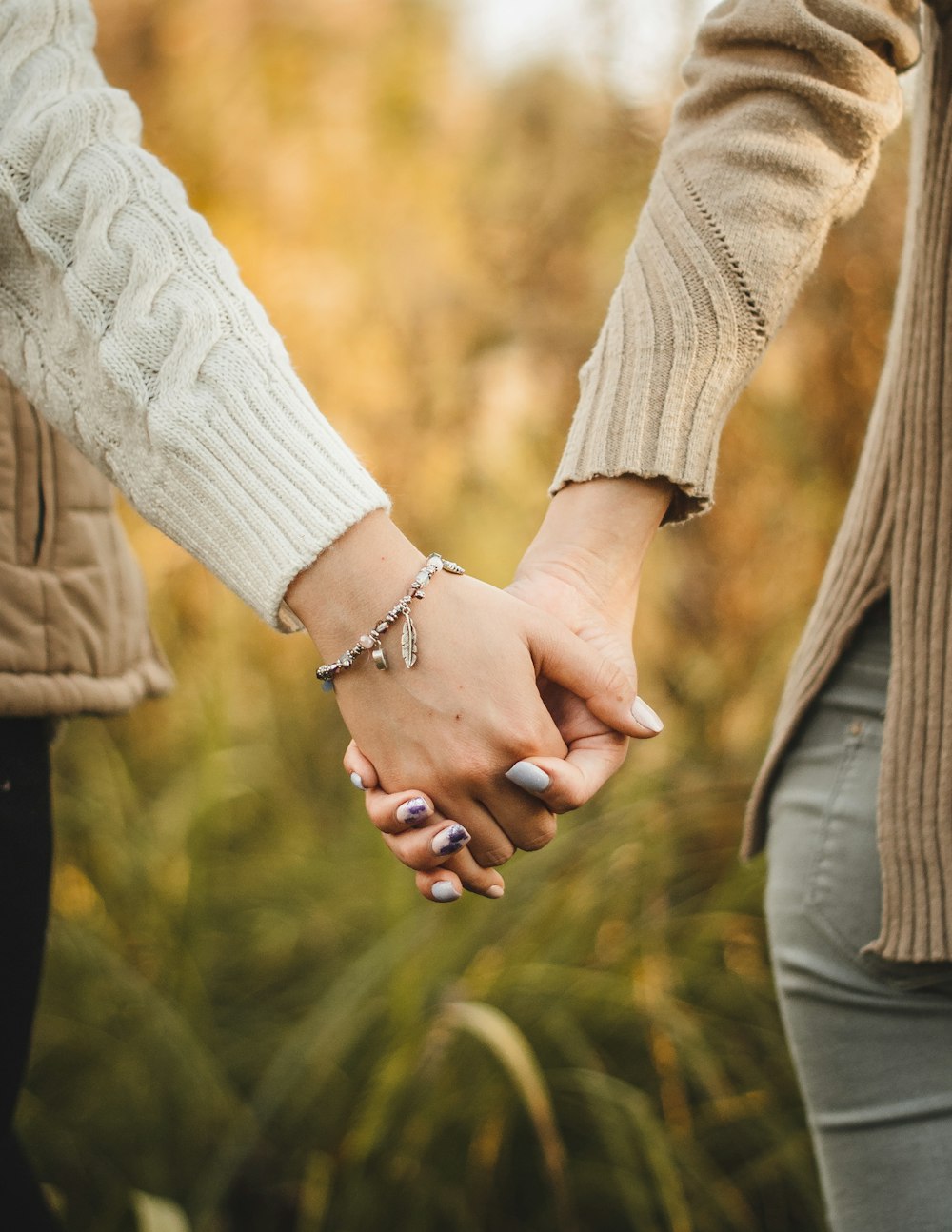 woman in white knit sweater holding hands with man in brown jacket
