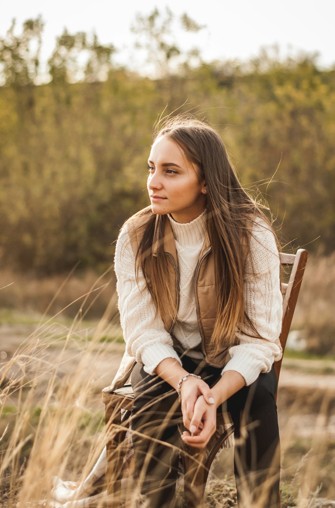 woman in beige long sleeve shirt and black pants sitting on brown wooden chair