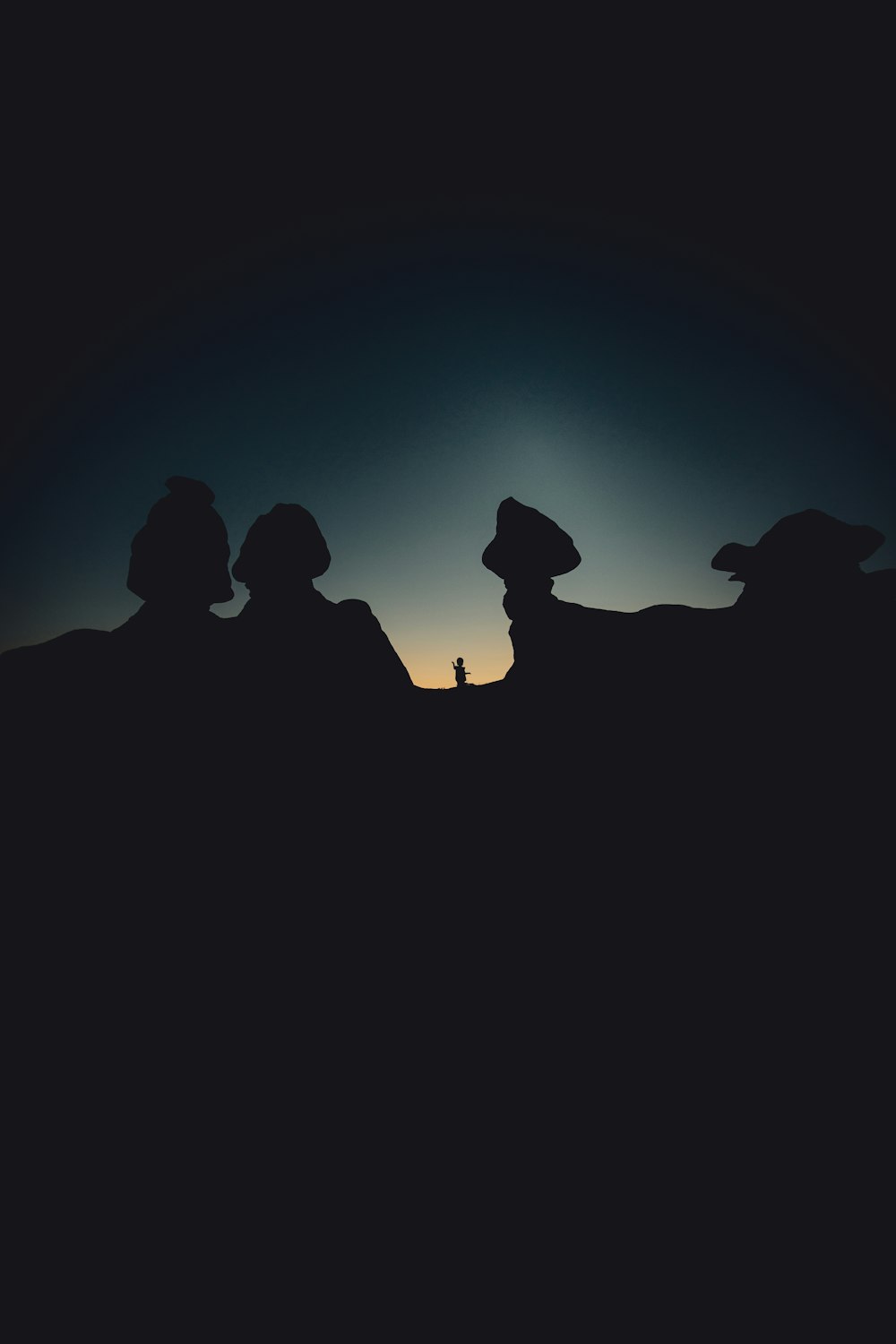 silhouette of people sitting on rock formation