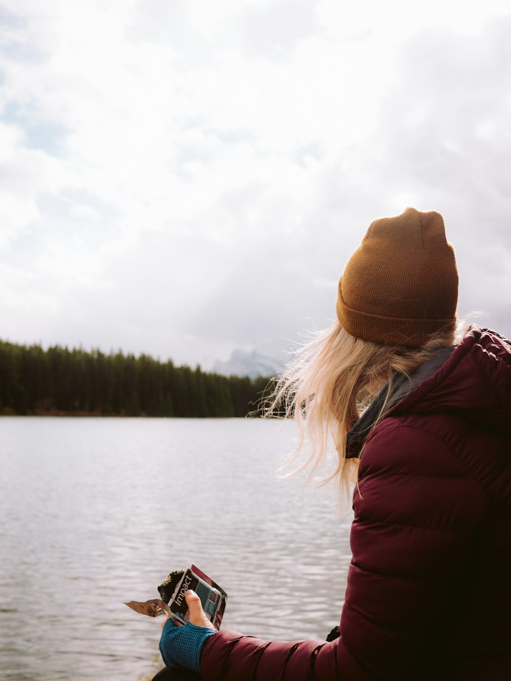 woman in red jacket and brown knit cap sitting on boat during daytime