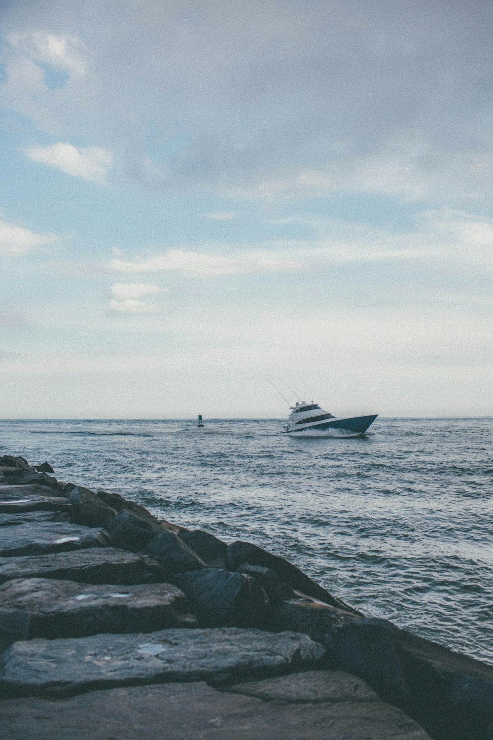 white and black boat on sea under white clouds during daytime