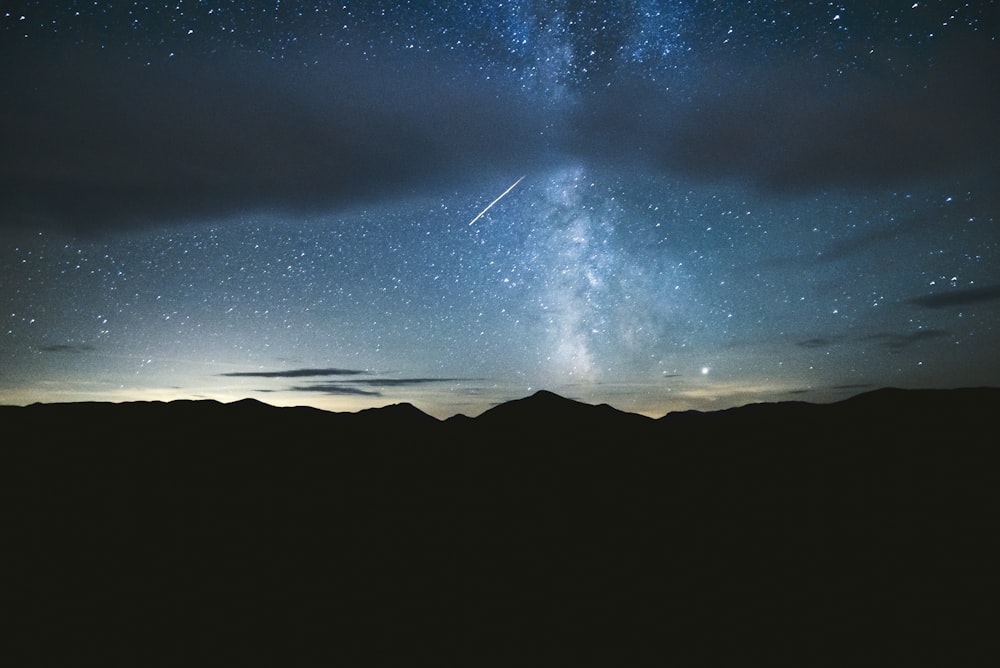 silhouette of mountain under starry night