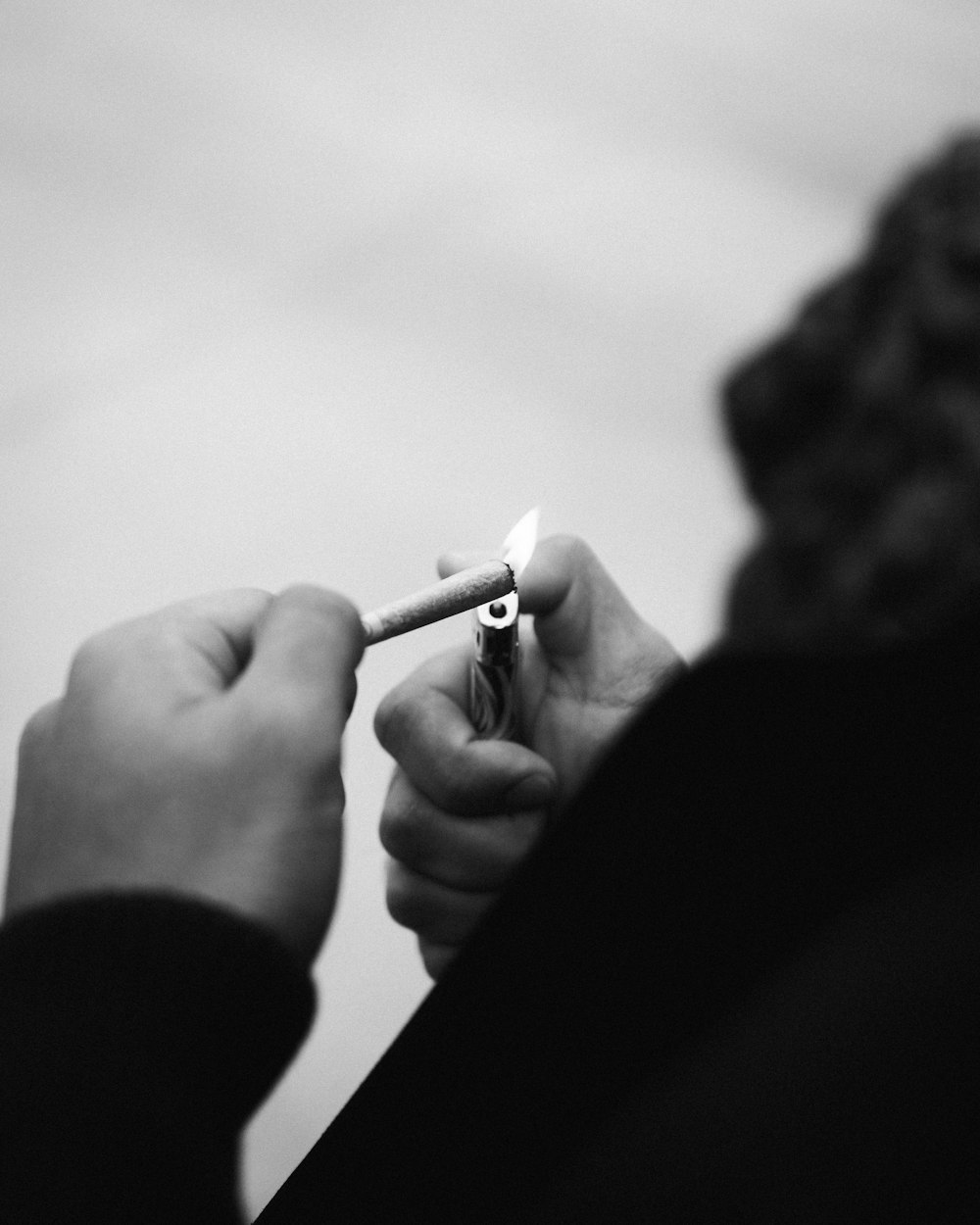 Foto en escala de grises de una persona fumando un cigarrillo