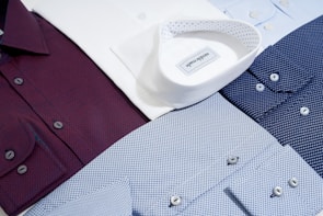 A selection of colorful, high-quality men's shirts neatly displayed on wooden hangers.