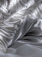 Close-up of a breathable, lightweight fabric blanket with a subtle pattern, folded neatly.