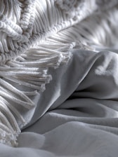 Close-up of handwoven Aubrac blankets folded neatly on a cozy bed.