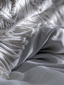 Close-up of a breathable, lightweight fabric blanket with a subtle pattern, folded neatly.