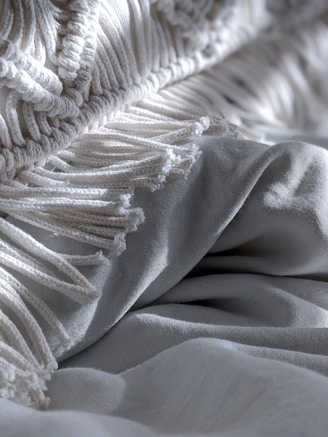 A cozy folded pink textile blanket with subtle embroidery on a light gray background.