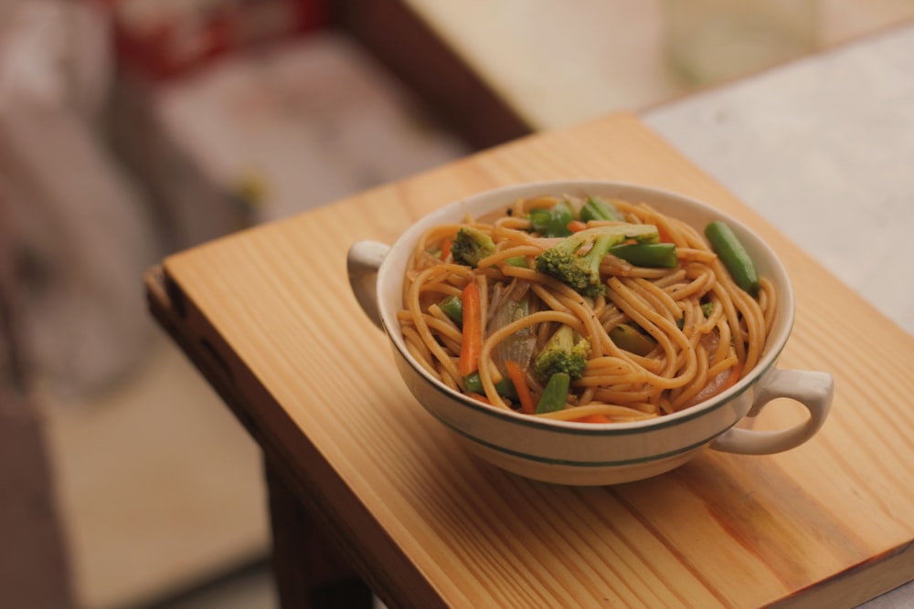 white ceramic bowl with noodles on brown wooden table